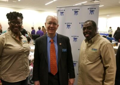 Two Bolingbrook STEM Association volunteers in tan shirts pose with a U.S. congressman at a STEM Night.